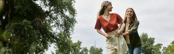 Лесбийская пара смеется вместе во время прогулки по зеленому парку в солнечный день. — стоковое фото