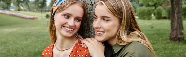 Una giovane coppia lesbica, con un sorriso in faccia, condivide un momento intimo in un parco. — Foto stock