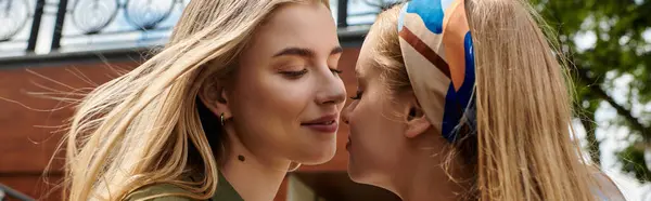 Two young women share a tender kiss in a green park, their faces filled with joy and love. — Stock Photo