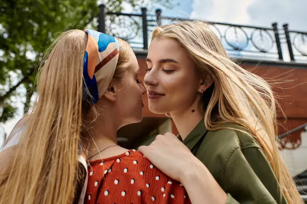 Two young women share a tender moment, their faces close together as they whisper secrets — Stock Photo