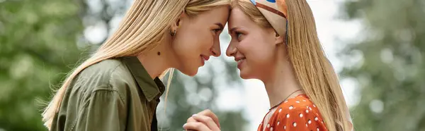 A young lesbian couple shares a tender moment, foreheads touching, during a sunny afternoon in a park. — Stock Photo