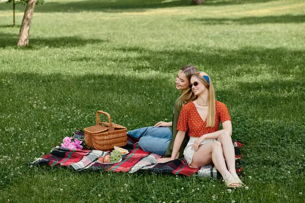 A lesbian couple enjoys a sunny afternoon picnic in a lush green park. — Stock Photo