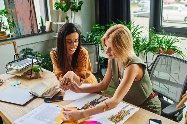 Two women in a cozy workspace discuss a project, looking confident and professional. — Stock Photo