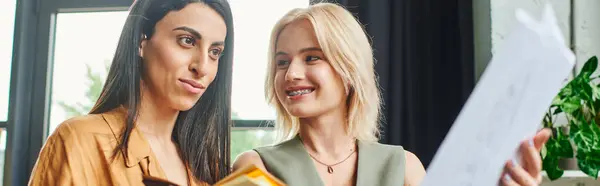 Two young women, lesbian couple, dressed in smart casual attire work on a project in a cozy modern office. — Stock Photo