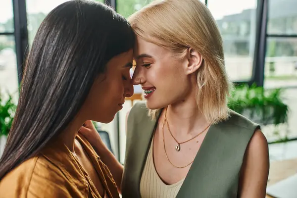 Two young women, colleagues and partners, share a tender moment in a modern, cozy office. — Stock Photo