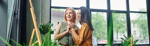 Zwei Frauen in schicker Freizeitkleidung arbeiten an einem Projekt in einem modernen Büro mit natürlichem Licht und viel Grün. — Stockfoto