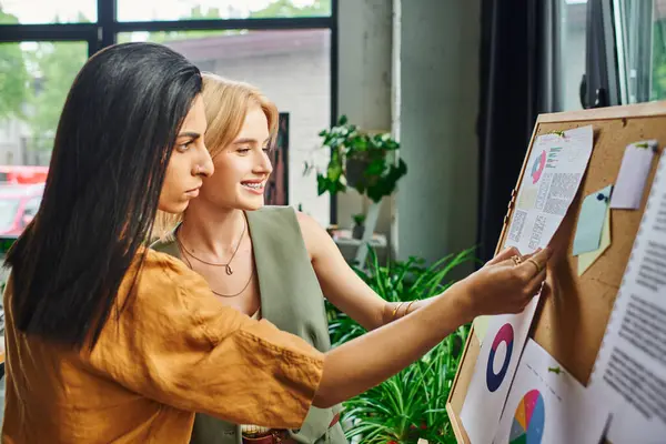 Two young women in smart casual attire work together on a project in a cozy workspace, lesbian couple — Stock Photo