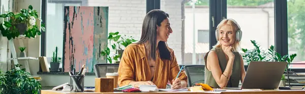 Two women in smart casual attire work on a project in a modern agency, looking confident and professional. — Stock Photo
