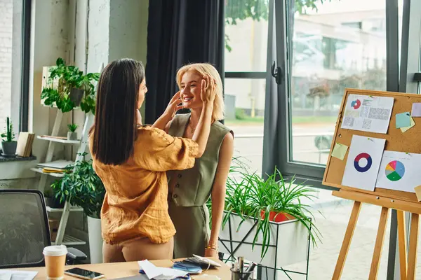 Two young women, dressed in smart casual attire, work on a project in a modern, cozy office setting. — Stock Photo