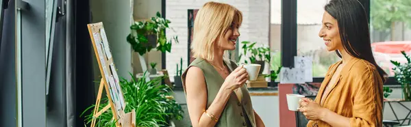 Lesbian couple in smart casual attire discuss a project while enjoying coffee in a cozy workspace. — Stock Photo