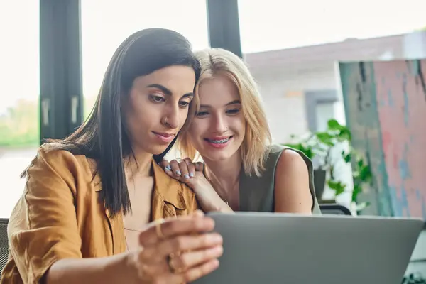 Two women, dressed in smart casual attire, look intently at a laptop screen in a cozy workspace. — Stock Photo