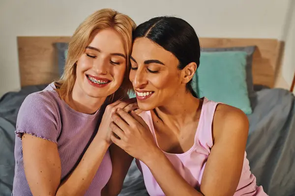 Ein lesbisches Paar umarmt sich glücklich auf einem Bett in seinem Haus und genießt einen Moment der Intimität und des Komforts. — Stockfoto