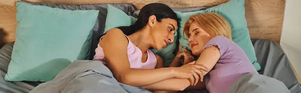 A lesbian couple shares a tender moment in their cozy home, wrapped in blankets and holding each other close. — Stock Photo