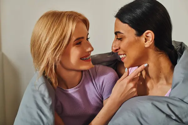 A happy lesbian couple cuddles under a blanket, enjoying a moment of intimacy. — Stock Photo