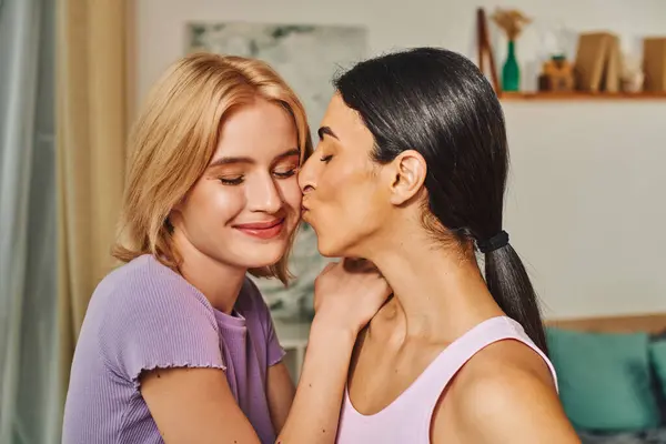 A happy lesbian couple shares a tender moment in their home, embracing each other with a kiss. — Stock Photo