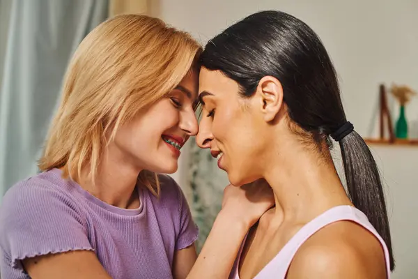 Two women, one with blonde hair and the other with dark hair, embrace each other in a loving hug inside a cozy home. — Stock Photo