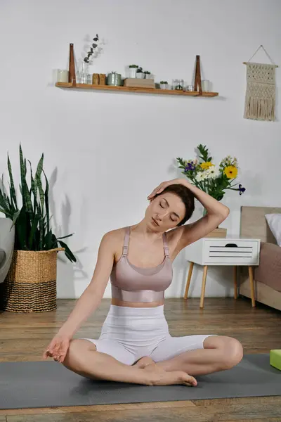 A woman in a crop top practices yoga and meditation in a modern apartment. — Stock Photo