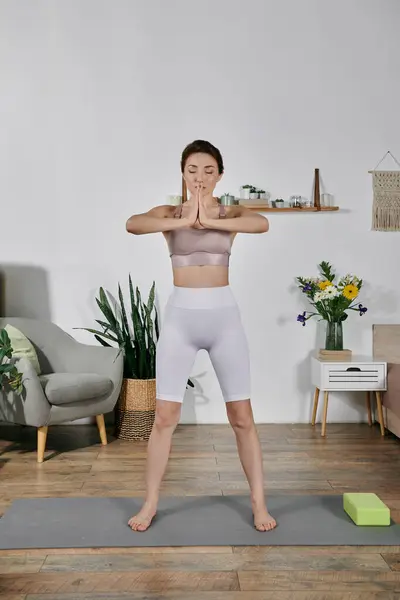 An Asian woman in a crop top meditates on a yoga mat in her modern apartment. — Stock Photo