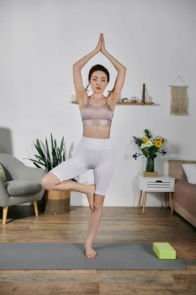 An Asian woman in a crop top does yoga in tree pose, eyes closed, meditating on her breath — Stock Photo