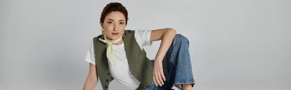 An Asian woman in a green vest and white t-shirt poses with a relaxed and stylish look, wearing a light scarf around her neck. — Stock Photo