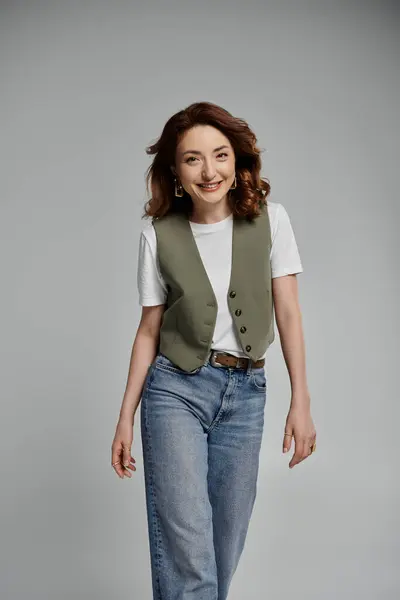 Uma jovem asiática sorri para a câmera, vestindo um colete verde, uma camiseta branca e jeans azuis.. — Fotografia de Stock