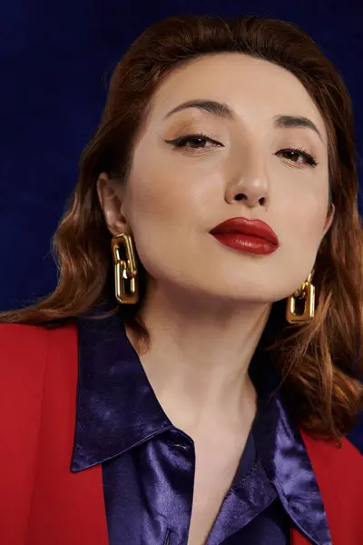 Una mujer elegante con el pelo largo, marrón que fluye lleva un traje rojo llamativo y una camisa de seda púrpura. — Stock Photo