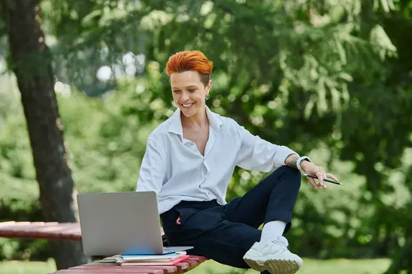 Eine Lehrerin sitzt auf einer Bank in einem Park und lächelt, während sie an einem Laptop arbeitet. — Stockfoto