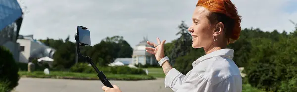 Un insegnante con i capelli rossi filma un vlog in un ambiente campus. — Foto stock