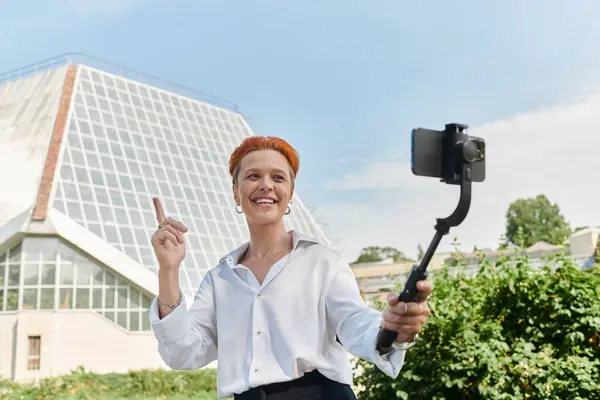 Una donna in camicia bianca registra un video con un selfie stick. — Foto stock