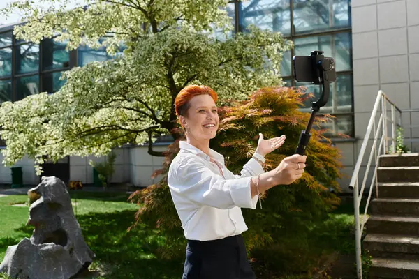Red-haired woman in white shirt takes selfie video on campus, smiling — Stock Photo