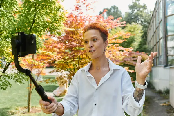 Una mujer con camisa blanca filma una videolección en el campus. - foto de stock