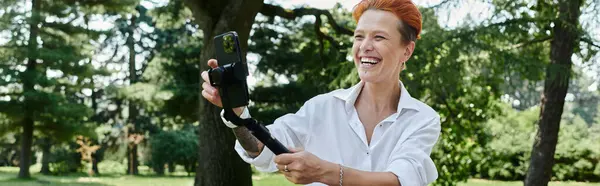 Um professor no campus desfruta de um momento de riso despreocupado enquanto segura um smartphone. — Fotografia de Stock