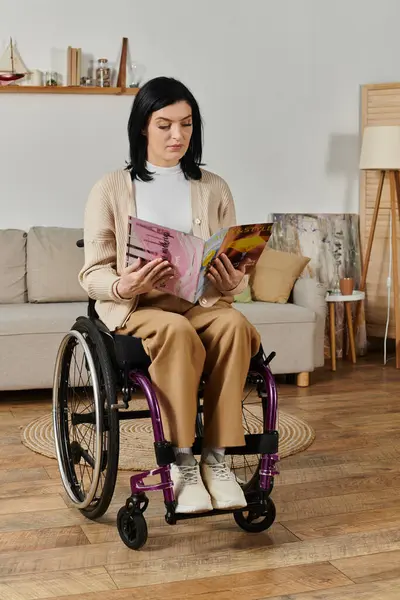 A woman sits in a wheelchair, engrossed in a magazine, in a living room. — Stock Photo