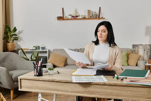 A woman in a wheelchair sits at a desk reviewing paperwork. — Stock Photo