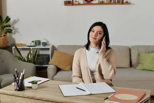 A woman sits in a wheelchair at a desk, making a phone call. — Stock Photo