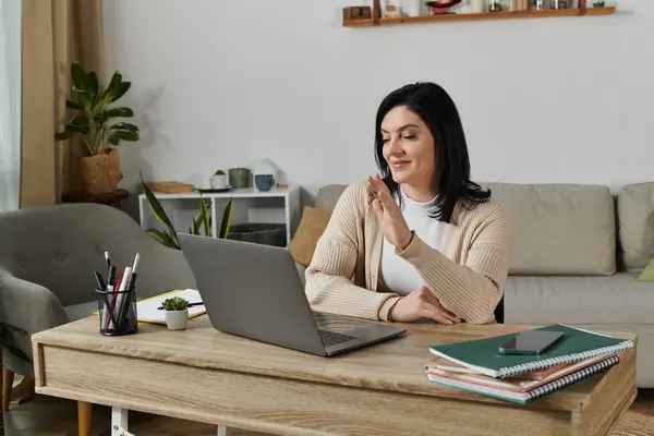 Eine Frau lächelt, als sie bei einem Videoanruf auf ihrem Laptop winkt. — Stockfoto