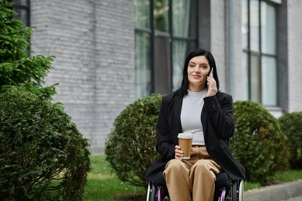 A woman in a wheelchair enjoys a coffee break while on a phone call. — Stock Photo