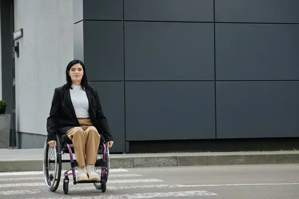 A woman in a wheelchair crosses a city street. — Stock Photo