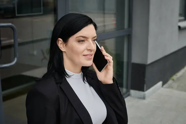 A woman in a wheelchair is smiling and talking on her phone outside a building. — Stock Photo