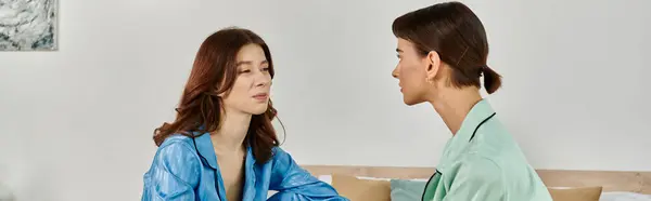 Two women in pajamas, looking at each other with tenderness, showcasing the intimacy of their relationship. — Stock Photo