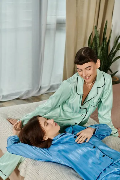 Un jeune couple de lesbiennes en pyjama partage un moment tendre sur un lit, rempli d'amour et d'affection. — Photo de stock