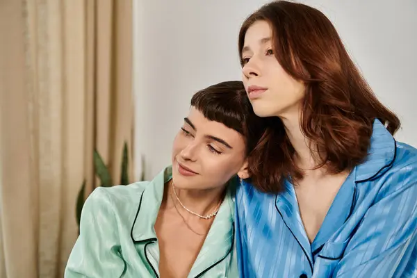 A young lesbian couple relaxes in their pajamas, sharing a tender moment of closeness. — Stock Photo