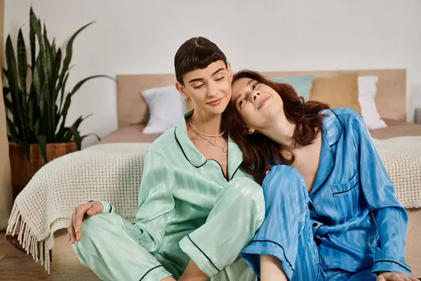 Un jeune couple lesbien en pyjama assorti partage un tendre moment de proximité dans sa chambre. — Photo de stock