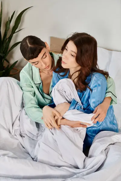 Two young women in pajamas cuddle in bed, sharing a tender moment in the morning light. — Stock Photo