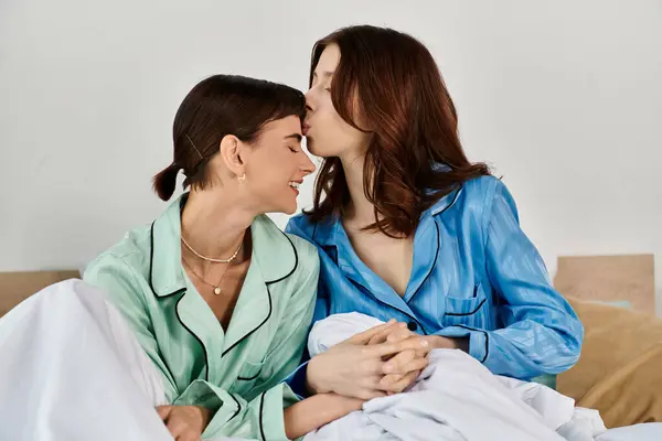 A young lesbian couple shares a tender moment in bed, their pajamas showcasing intimacy and comfort. — Stock Photo