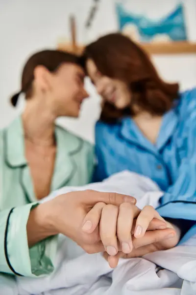 Two women in pajamas, intertwined hands, showcasing their love and connection on a bright morning. — Stock Photo
