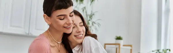 Two young women embrace in the kitchen, their faces radiating warmth and affection. — Stock Photo