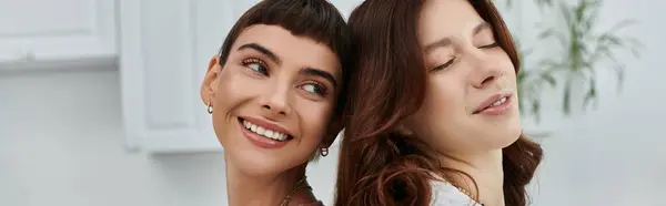 Dos mujeres jóvenes comparten un tierno abrazo a la luz de la mañana, sus rostros irradian felicidad y amor. - foto de stock