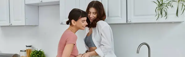 A young lesbian couple shares a tender embrace in their kitchen, their love and connection evident in their morning glow. — Stock Photo