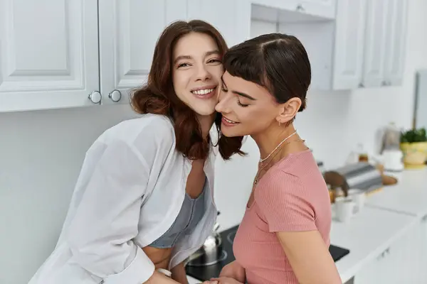 A young couple enjoys a tender moment in their kitchen, sharing a warm embrace. — Stock Photo